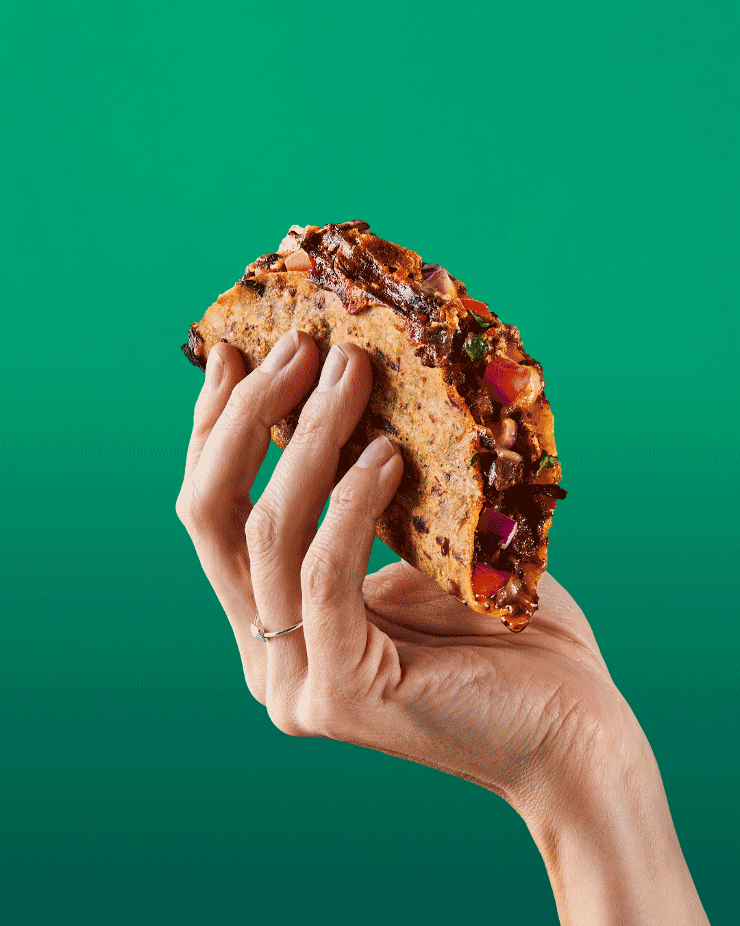 A hand holding a loaded Salsas birria taco dripping with consommé